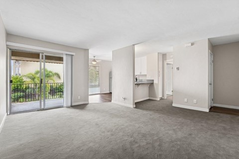 A spacious living room with a sliding glass door leading to a backyard.