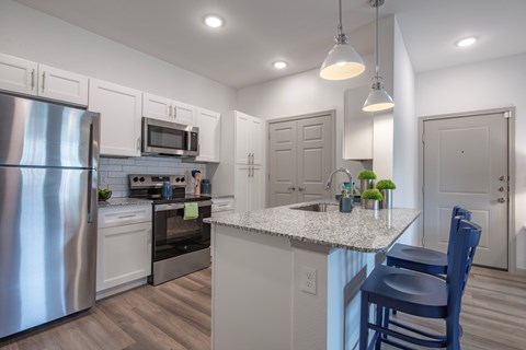 A kitchen with a stainless steel refrigerator, microwave, oven, and sink.