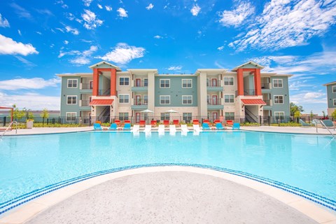 A large swimming pool in front of a multi-story apartment building.