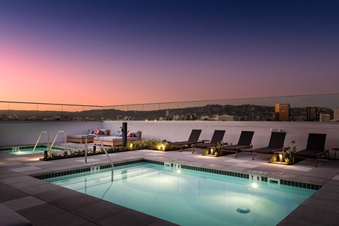 A swimming pool with lounge chairs and a sunset view.