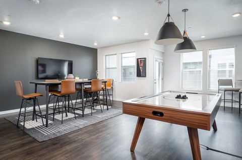 a living room with a pool table and a bar with chairs and a television