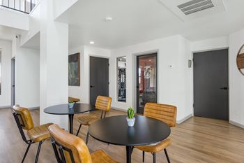 A black table with four chairs in a white room.