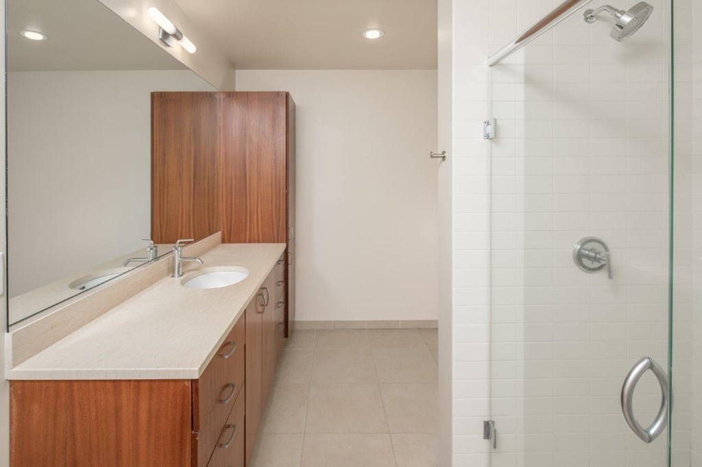 A bathroom with a sink, mirror, and wooden cabinet.