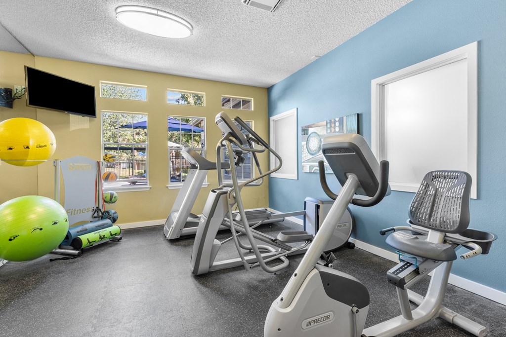 a gym with exercise machines and a yellow and blue wall