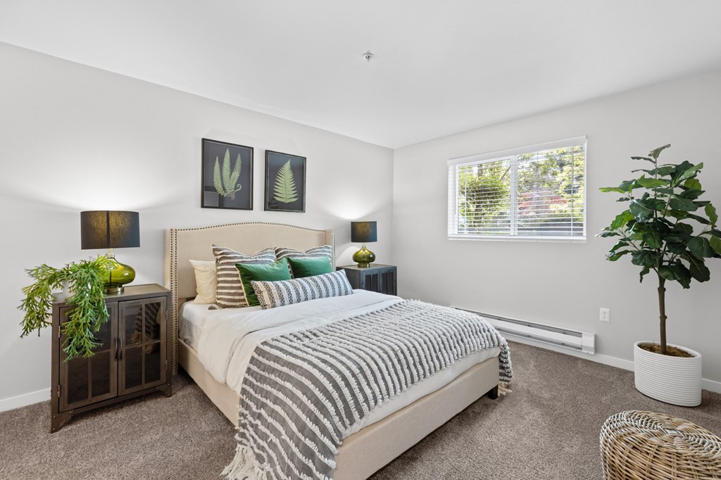 a bedroom with a large bed and plants on the side of the bed
