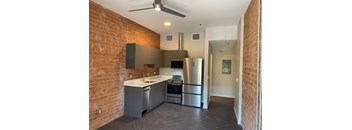 A kitchen with a brick wall and stainless steel appliances.