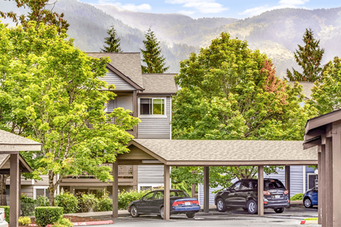 A carport with a car and a truck parked in front of a house.
