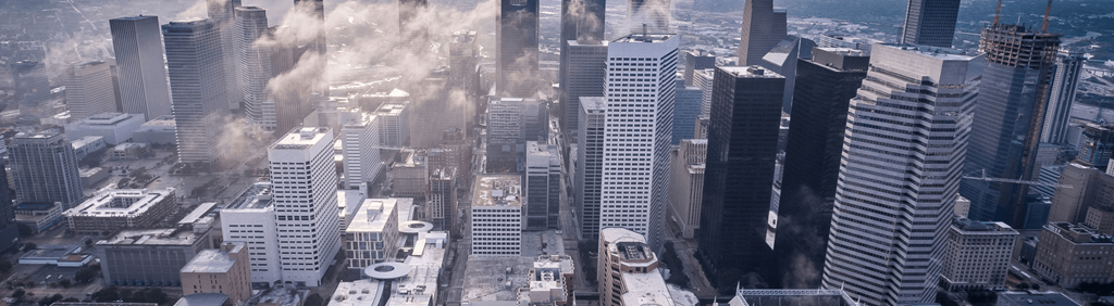 A city skyline with tall buildings and a smoky haze.