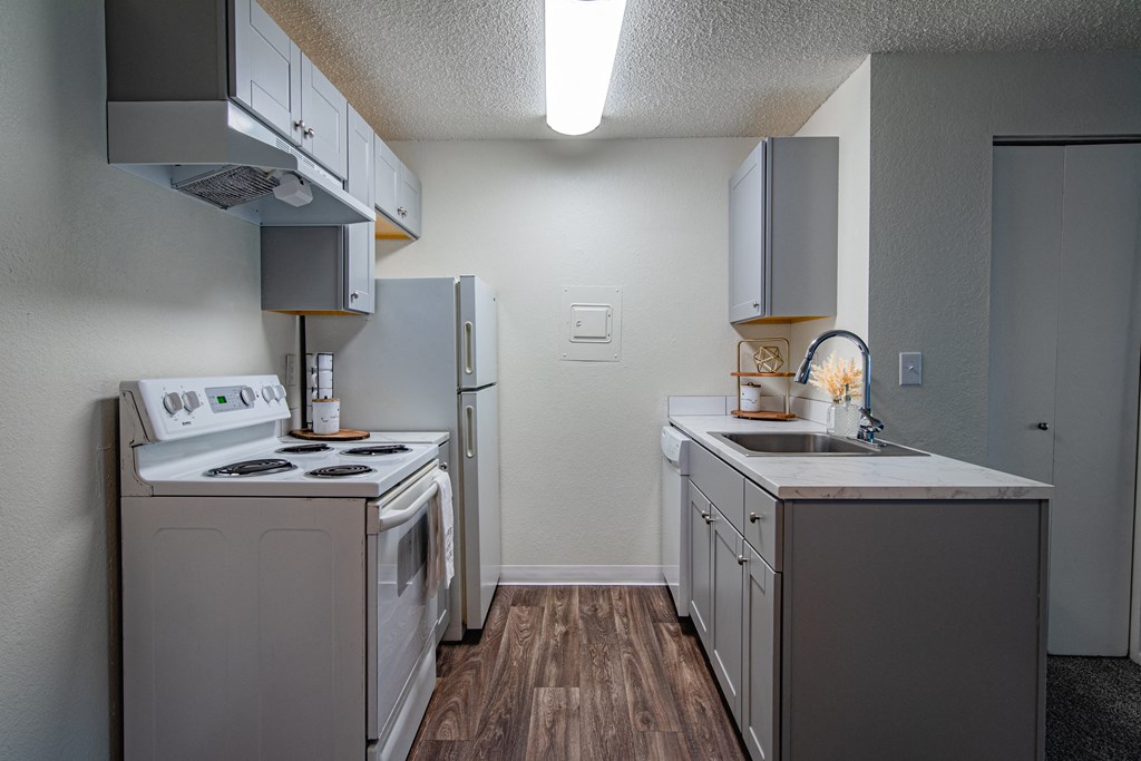 The Willows Apartments kitchen with white appliances and white cabinets and a white refrigerator and stove and sink