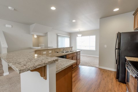 A kitchen with granite countertops and a black refrigerator.