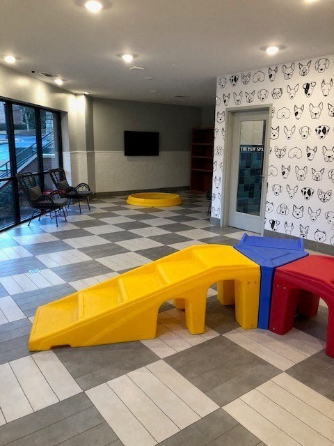 A room with a checkered floor and a white wall with black cat drawings.