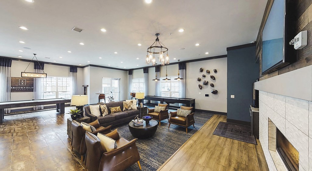 Spacious resident clubhouse with television, fireplace, couches, and pool tables.