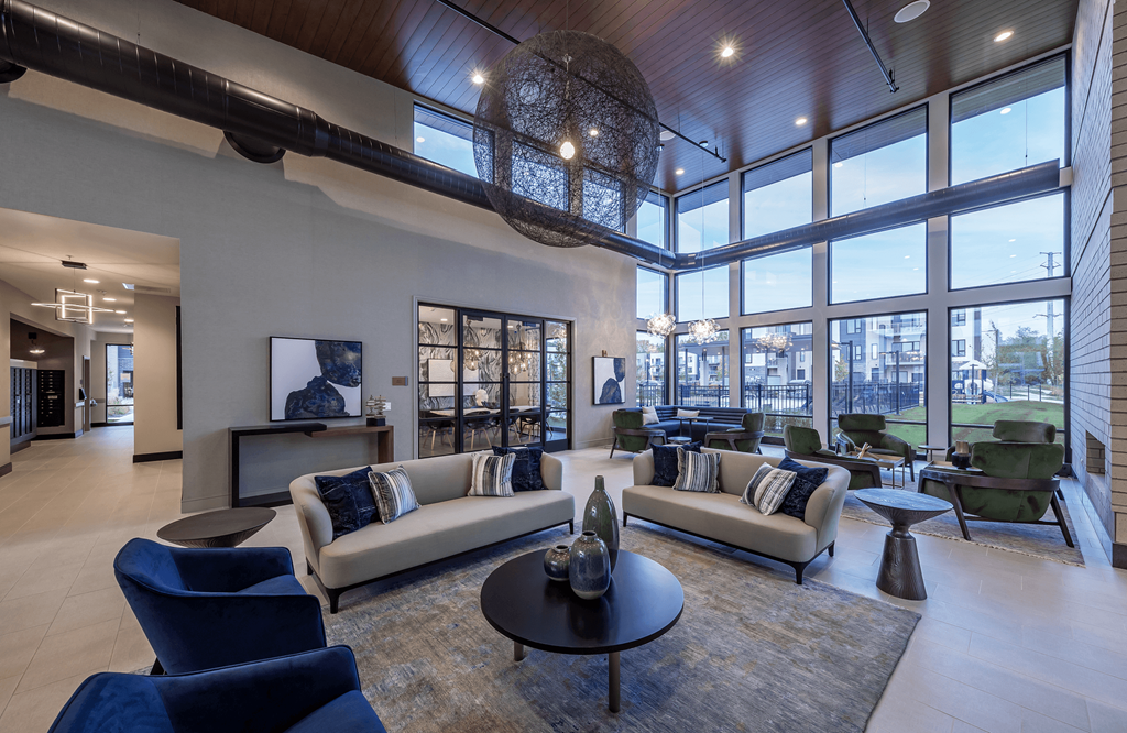 a living room with couches and a table     and large windows