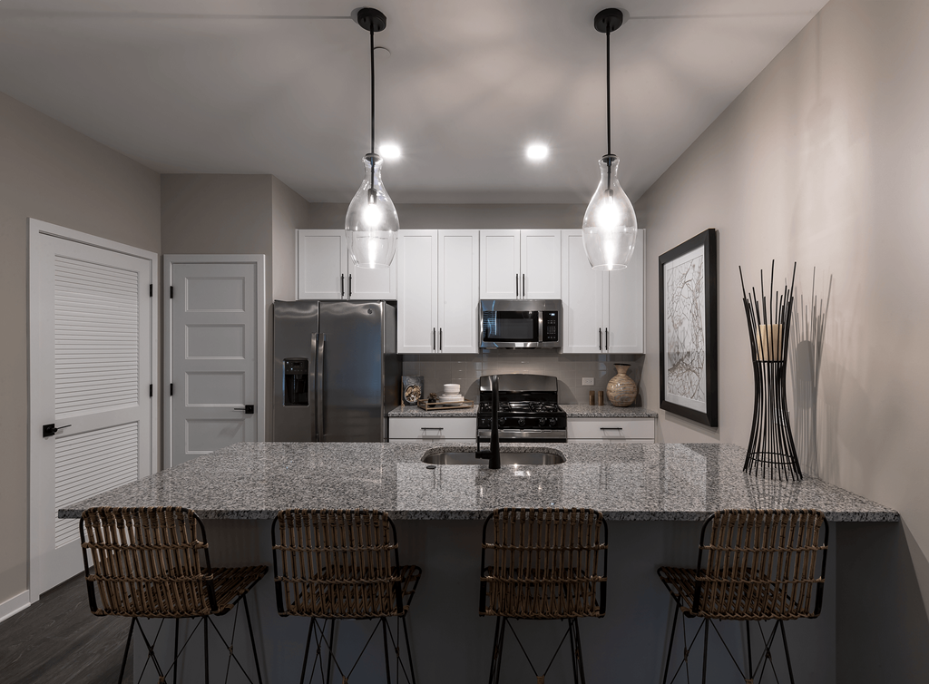 an open kitchen with a granite counter top and a bar with 5 chairs