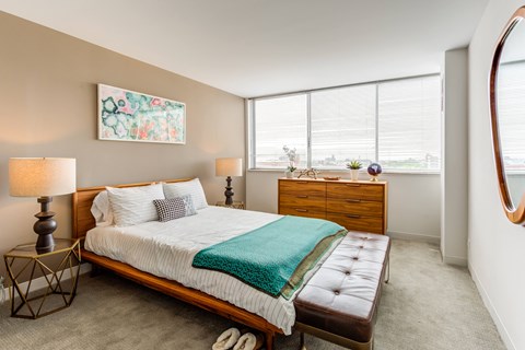 a bedroom with a bed and a dresser and two windows