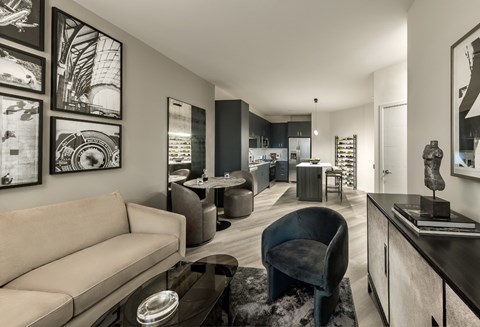 A modern living room with a beige sofa, a black chair, and a coffee table.