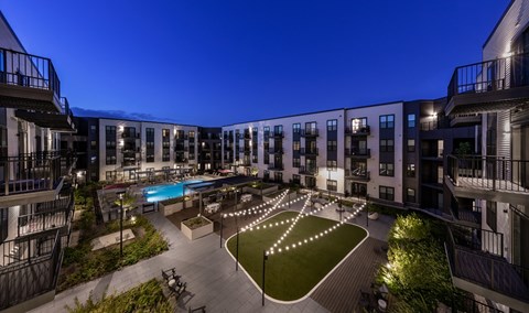 A courtyard with a pool surrounded by buildings at night.