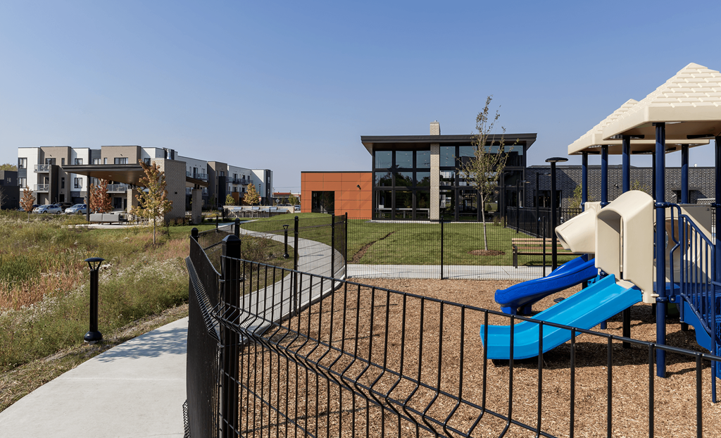 a playground with a swing set and a gazebo in front of apartments