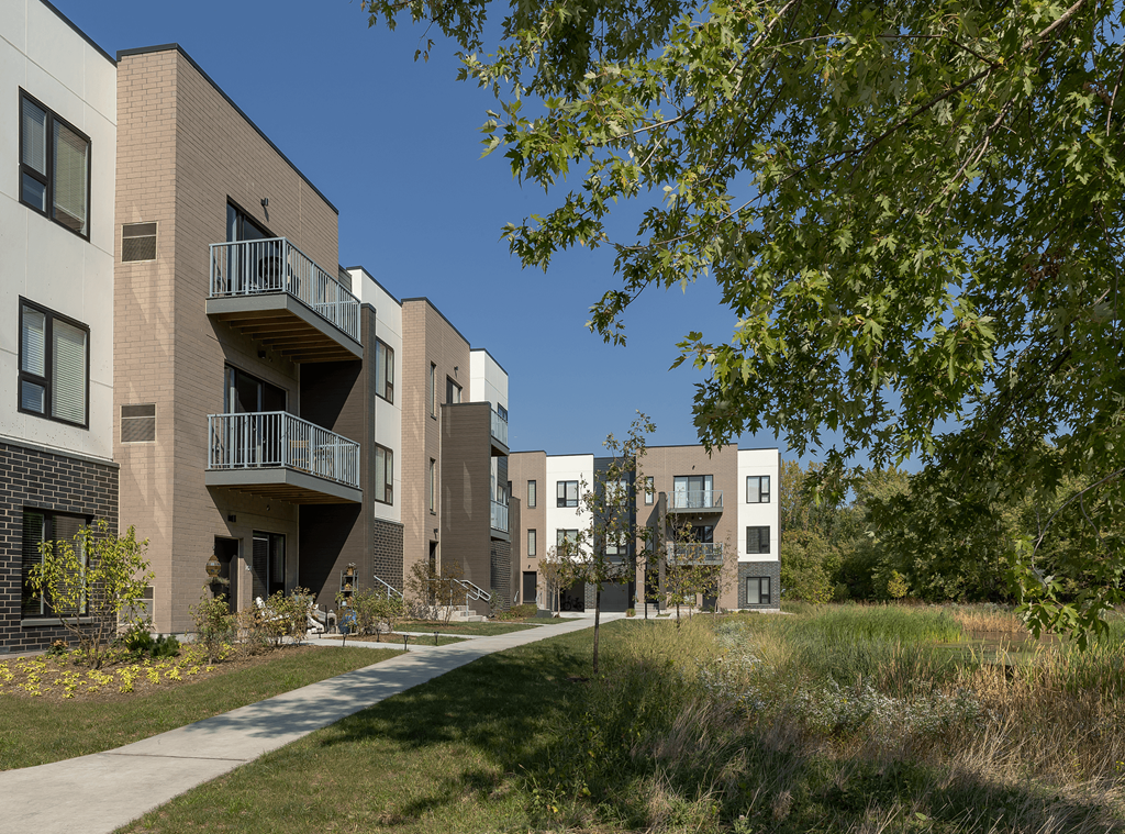 a row of apartment buildings with a sidewalk
