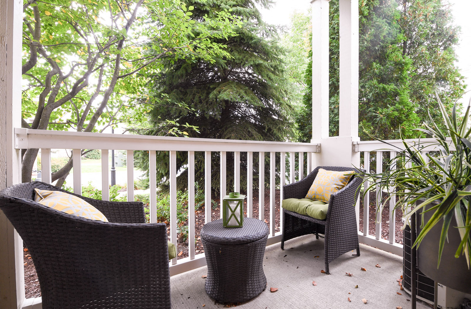 a porch with two chairs and a table and some trees