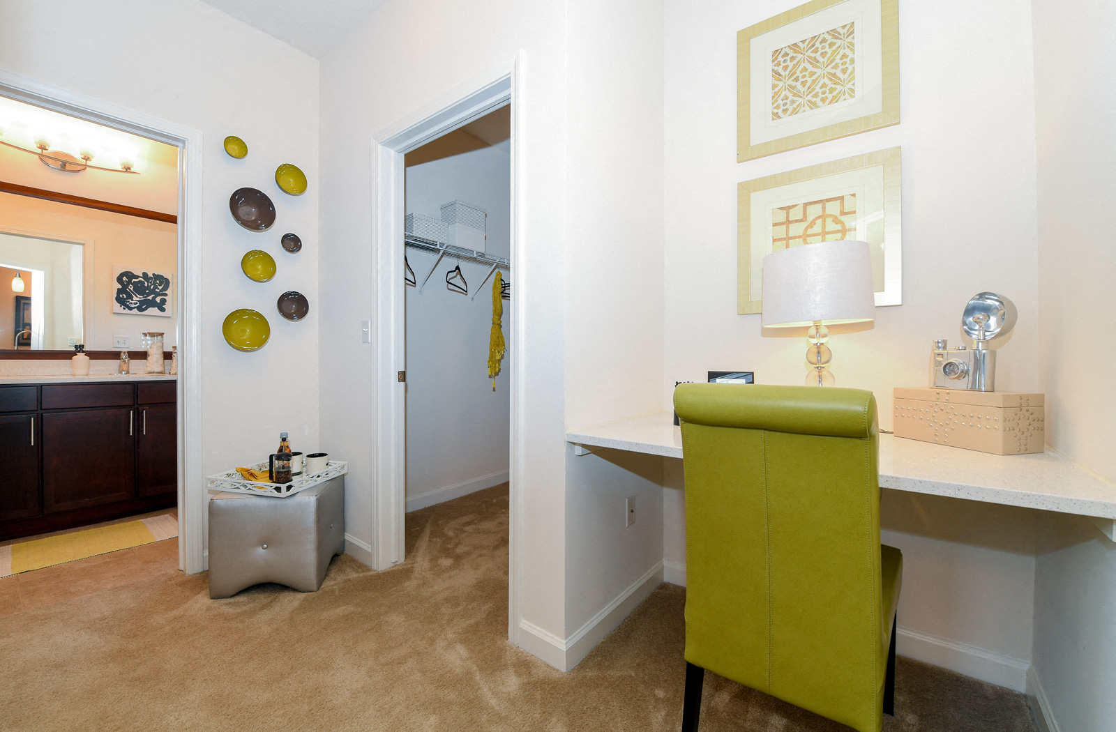 a living room with a green chair and a desk and a bathroom