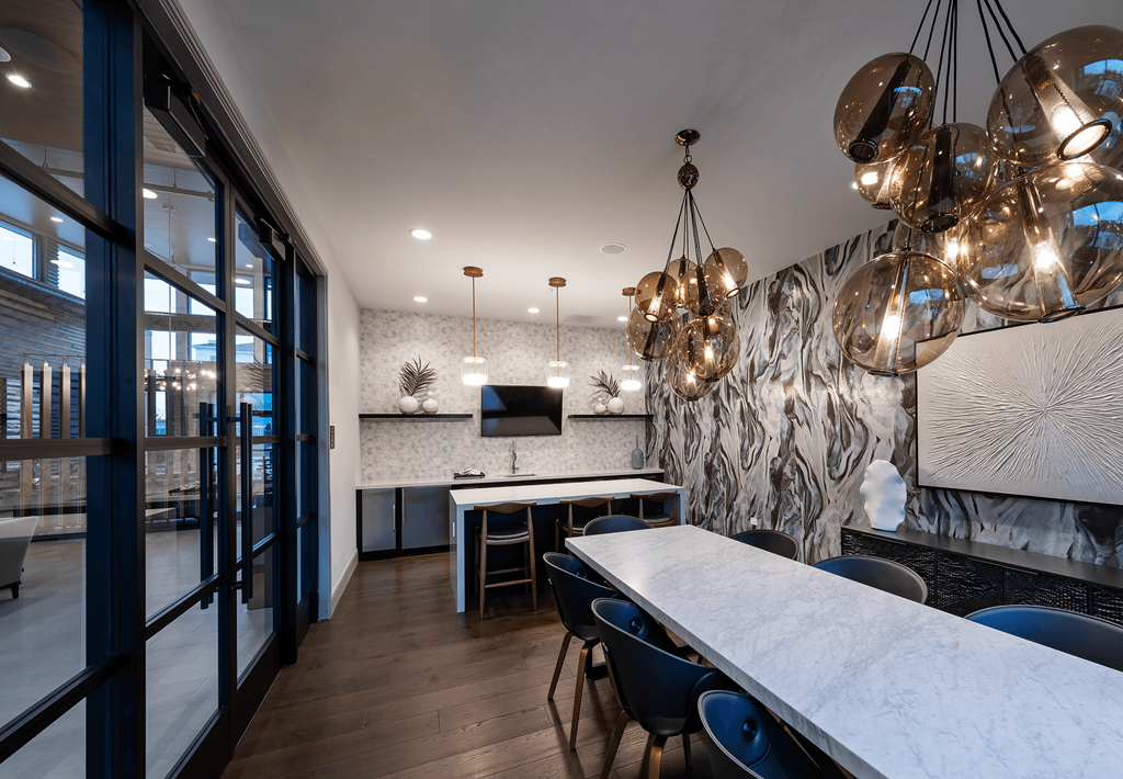 a dining room with a marble table and chairs and a kitchen with a tv