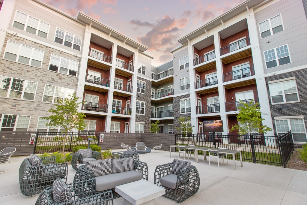 Outdoor lounge area surrounded by apartments during sunset.