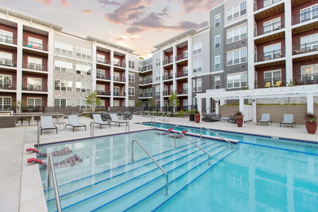 Pool area with apartments surrounding it during sunset.