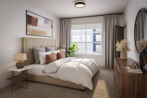 A well-lit bedroom with a large bed, a side table with a lamp, and a dresser with a mirror.