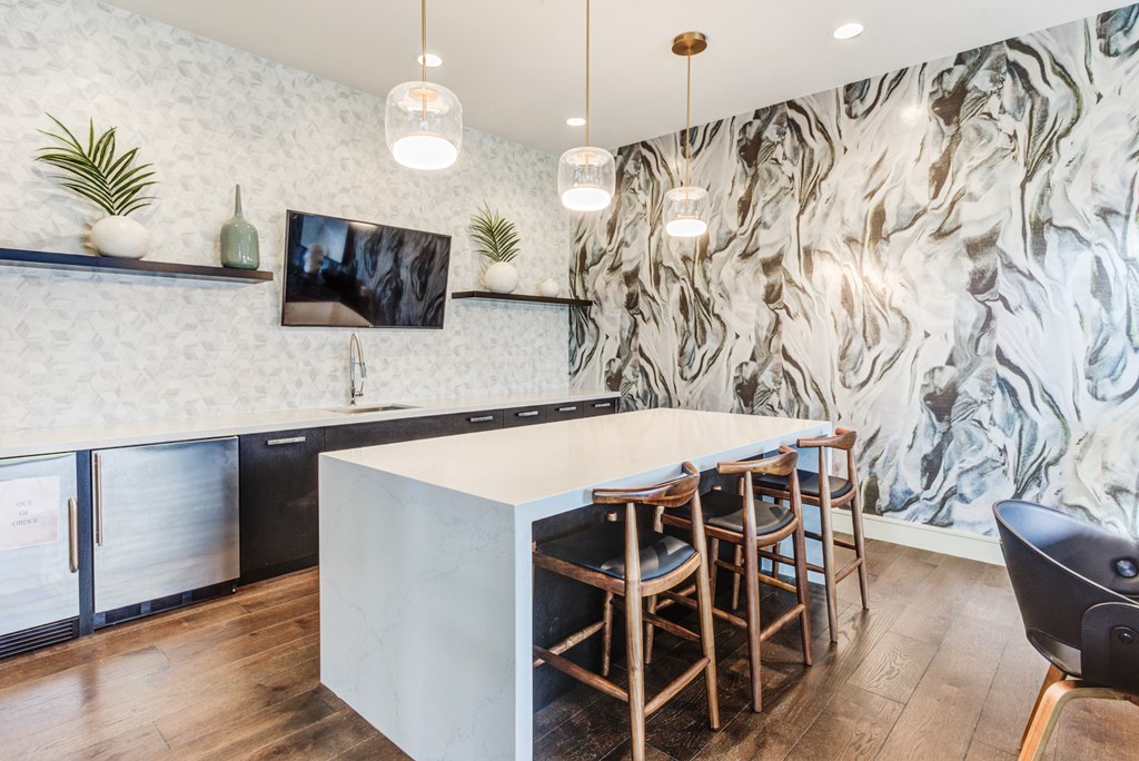 a kitchen with a large white counter top and chairs
