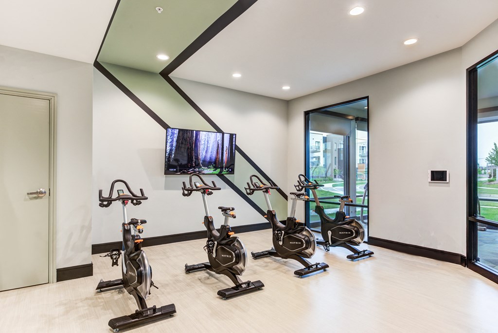 a gym with exercise machines and a tv on the wall