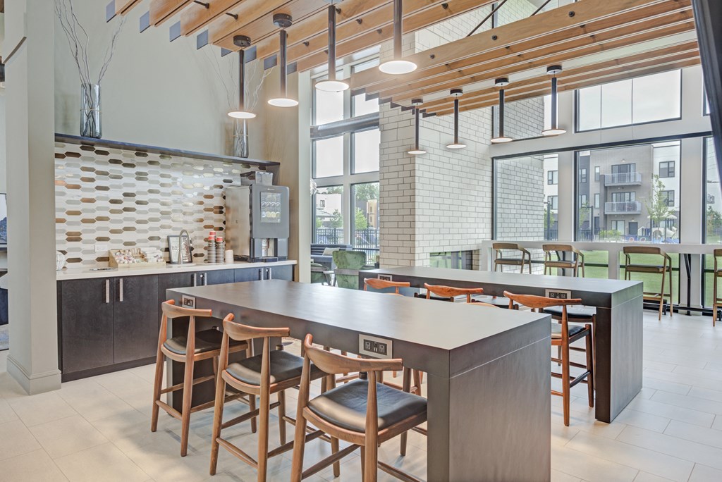a communal table and chairs in a restaurant with large windows