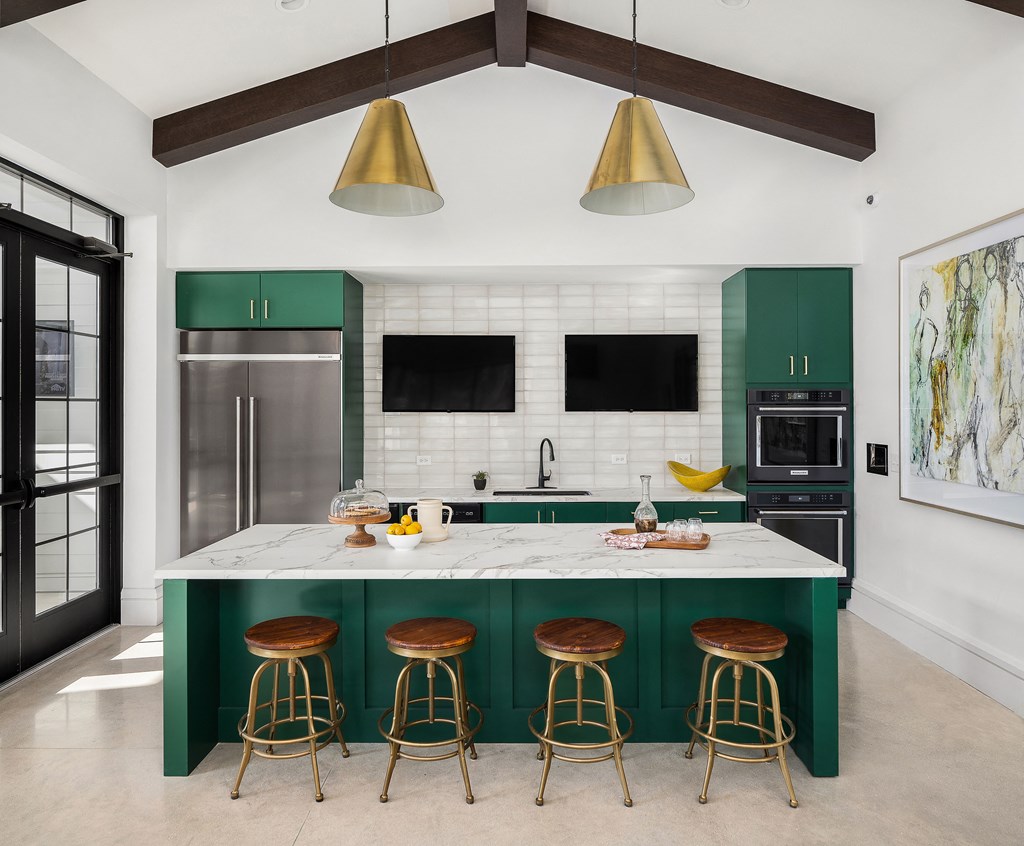 A kitchen with a white marble countertop and green bar stools.