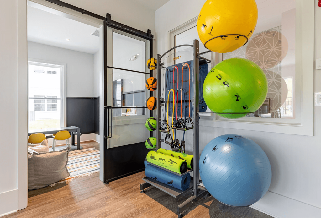 a gym with a ball and weights in a room with a glass door