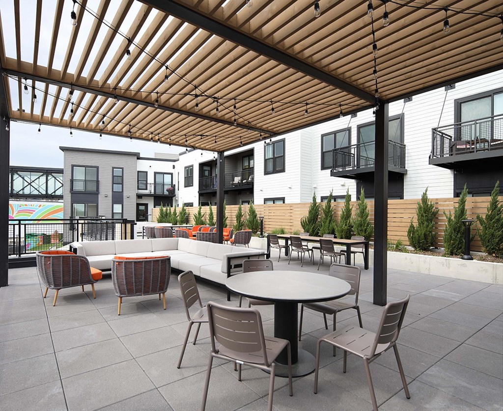 an outdoor patio area with tables and chairs and buildings in the background