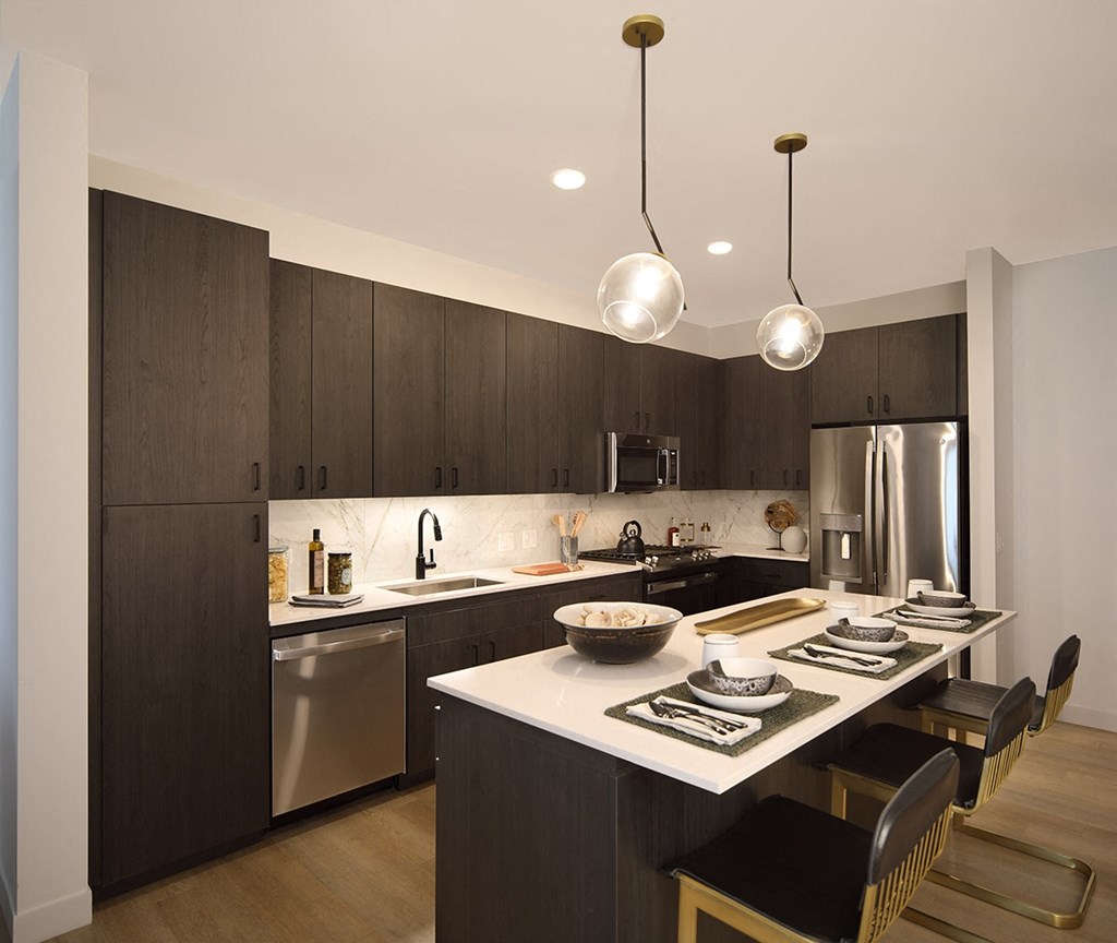 a kitchen with a large island and a stainless steel refrigerator