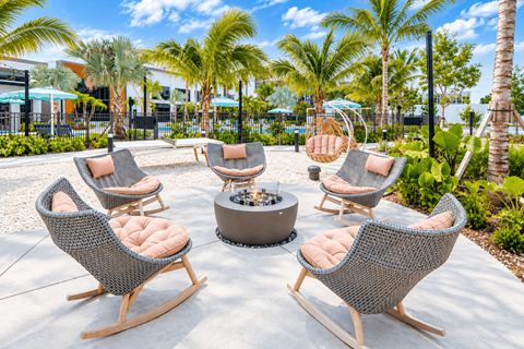 A set of chairs and a table are arranged around a fire pit on a patio.