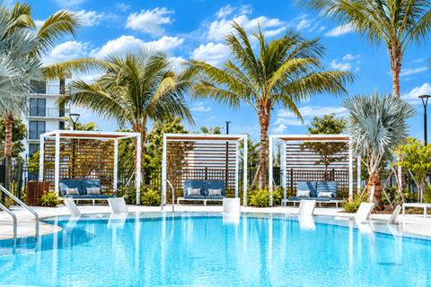 A pool surrounded by palm trees and lounge chairs.