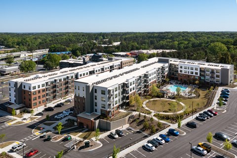 an aerial view of an apartment complex with a pool and parking lot