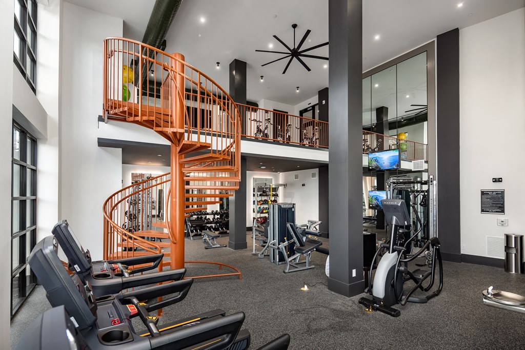 a spiral staircase in a gym with weights and cardio equipment