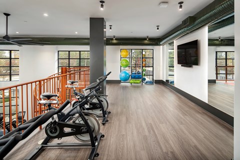 a workout room with exercise bikes and a colorful ball on the wall