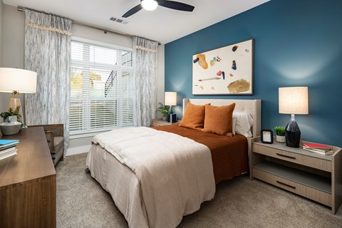 a bedroom with blue walls and a bed with orange pillows