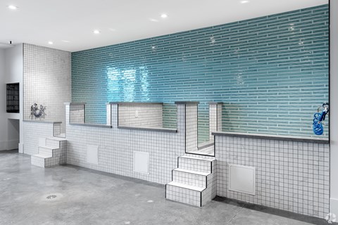 A bathroom with a blue tiled wall and white tiled floor.