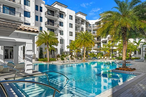 a swimming pool with palm trees in front of an apartment building