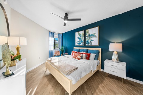 a bedroom with a bed and a blue wall and a ceiling fan