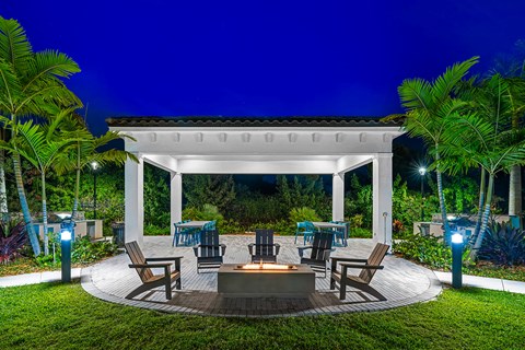 a patio with tables and chairs and a pavilion at night