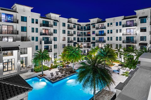 a building with a pool and palm trees in front of it