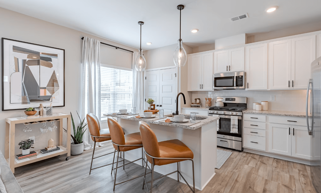 an open kitchen and dining area with white cabinets and stainless steel appliances
