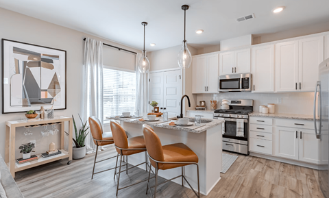 an open kitchen and dining area with white cabinets and stainless steel appliances