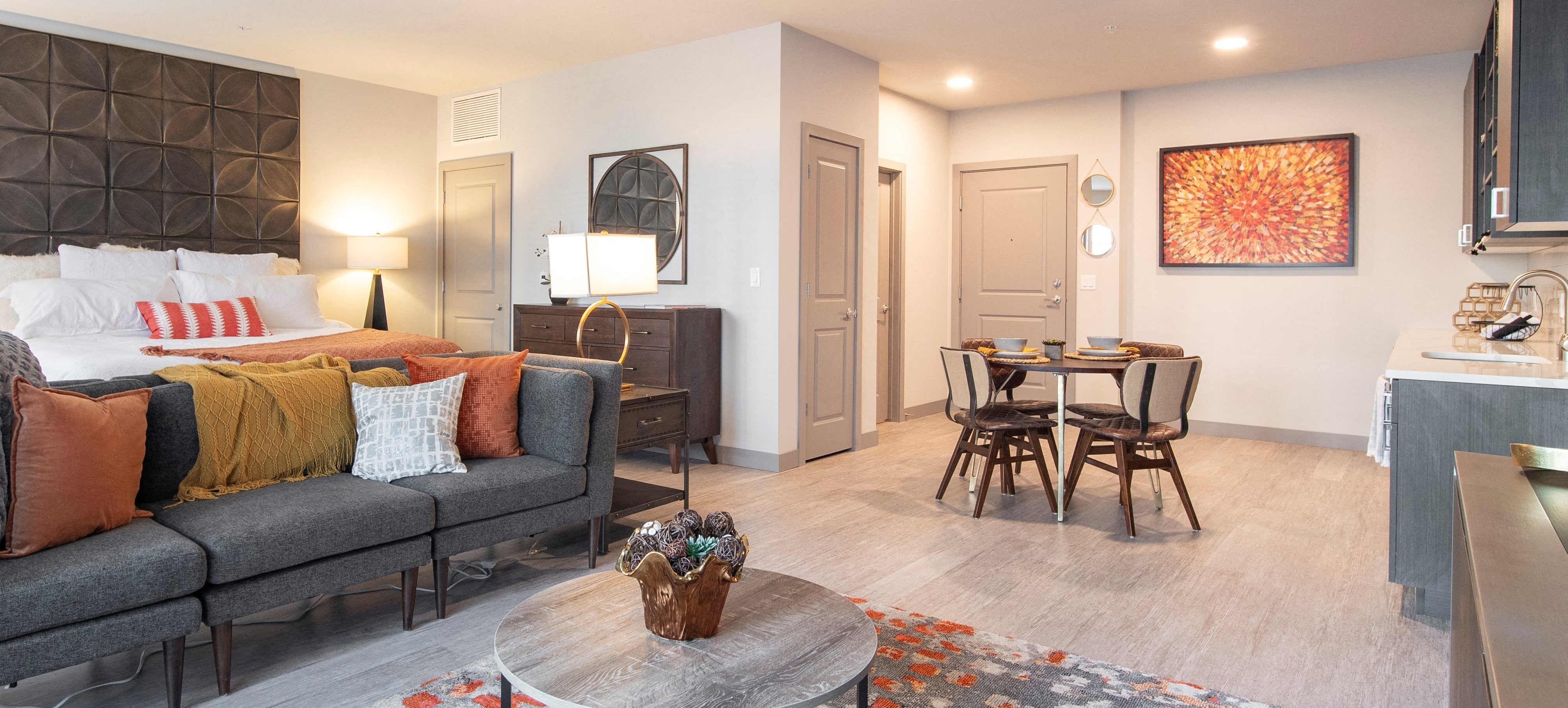 Decorated studio apartment with bed, couch, and dining table with furnished kitchen